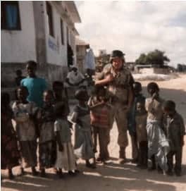 a soldier standing in front of a group of children.