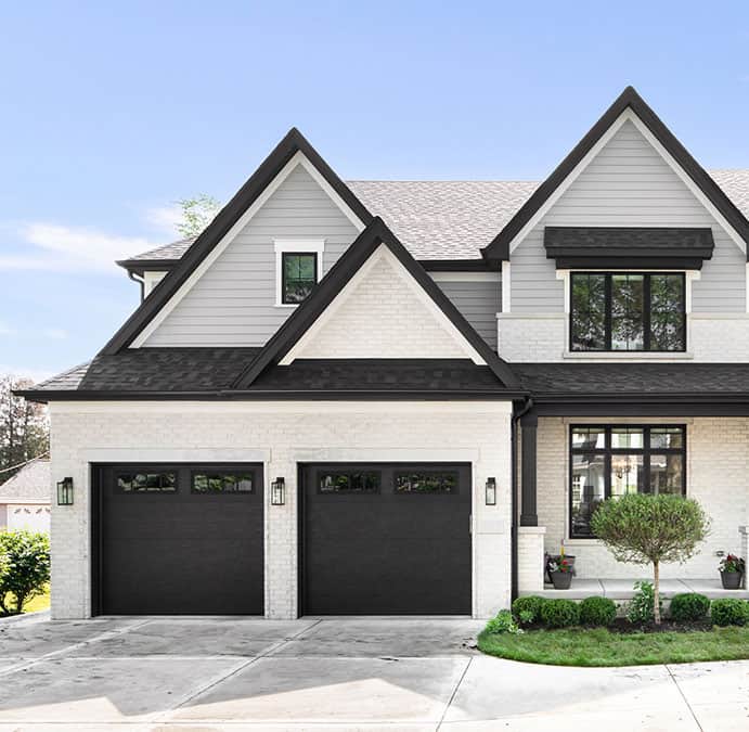 a white and black house with two black garage doors.