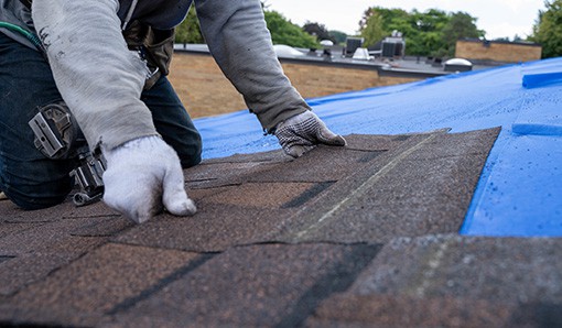 a man working on a roof with a blue tarp.