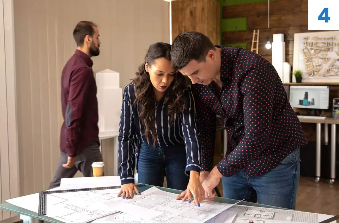 A couple reviewing blueprints on a table during a professional consultation for remodeling services.