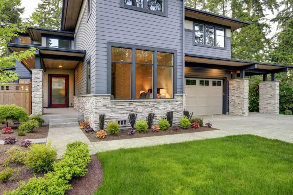 a modern home with gray siding and landscaping.
