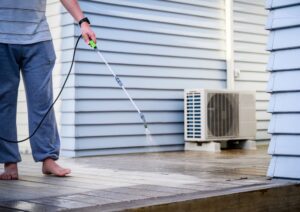 Man cleaning wooden deck with hand-held pressure sprayer