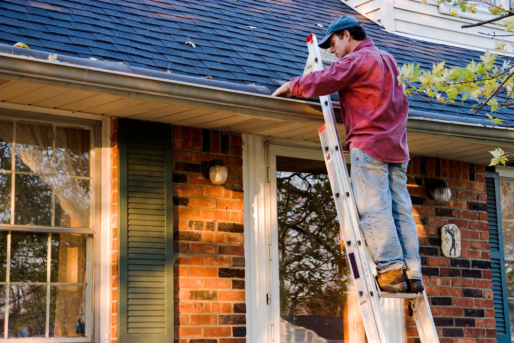 man practicing gutter cleaning safety while on ladder