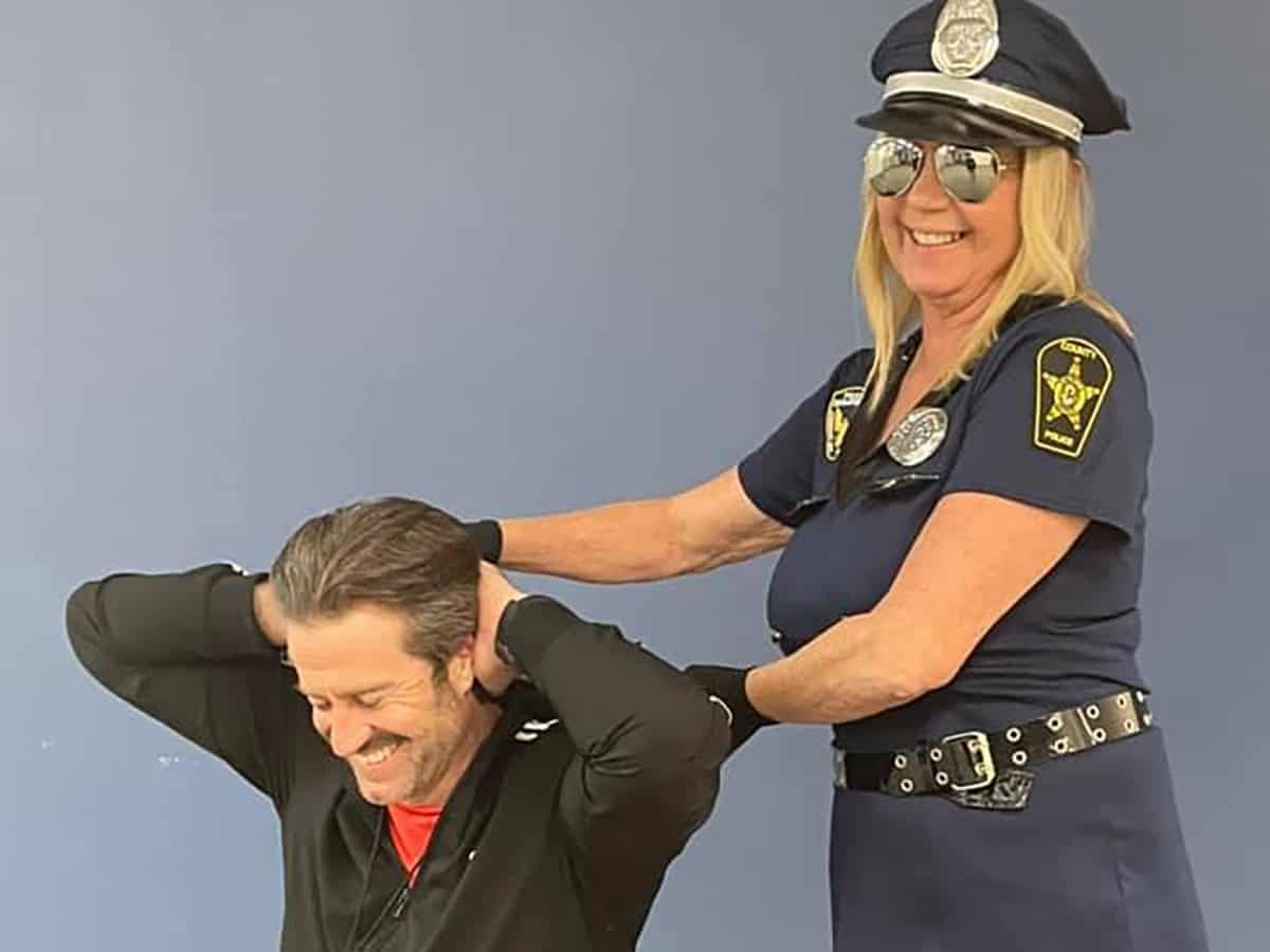 a police officer helping a woman put on her hat.