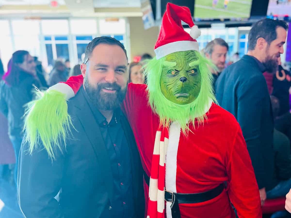 a man in a santa suit and a man in a green costume pose for a.